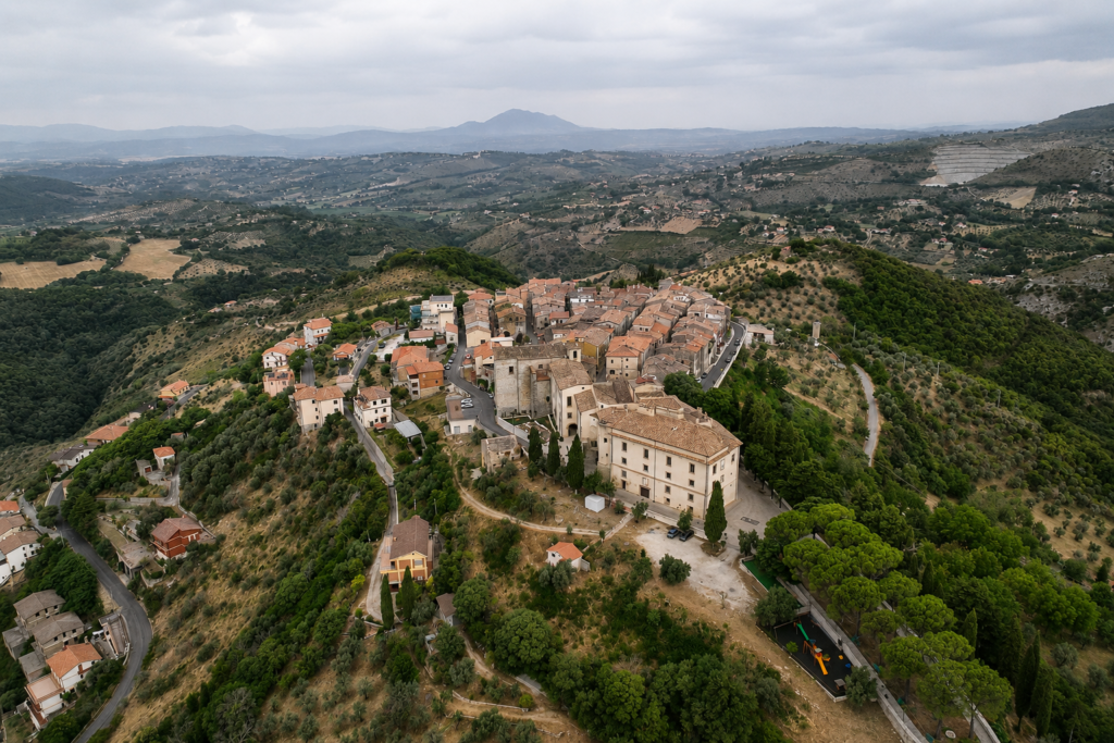 Veduta panoramica di Mompeo, borgo della Valle del Farfa, con centro storico in pietra, Castello Orsini Naro, oliveti, boschi e colline sabine.